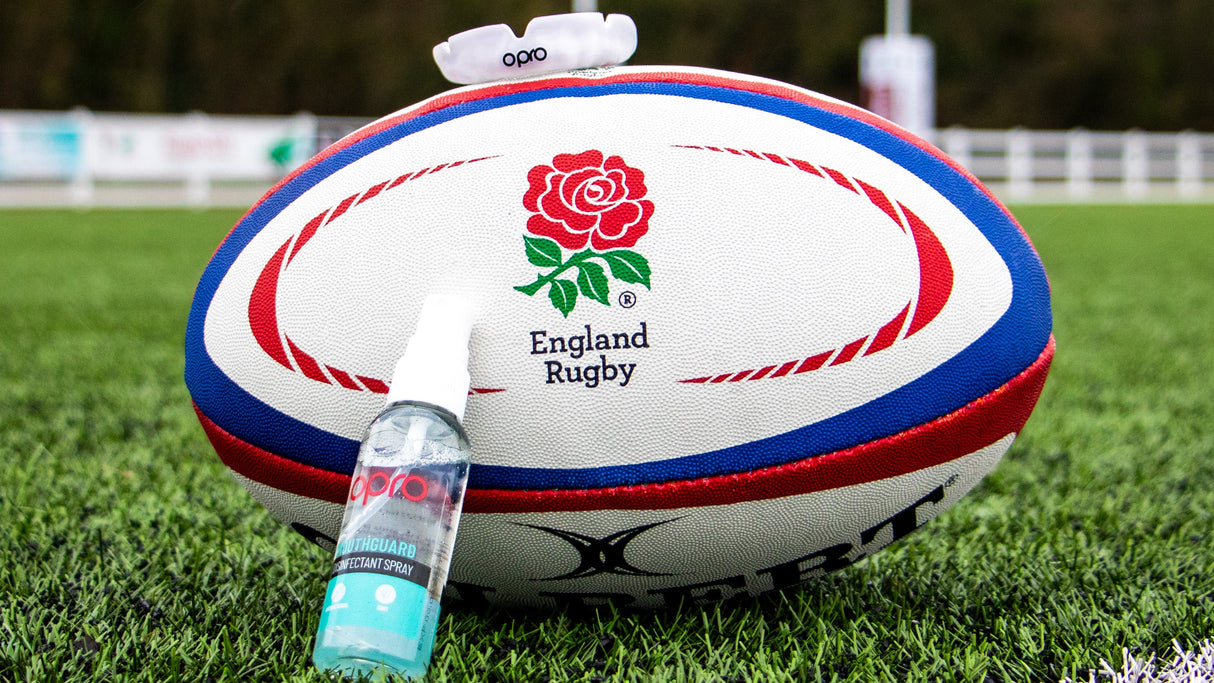 England Rugby ball with OPRO Clenaing spray on a grass field