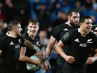 New Zealand rugby players in black jerseys celebrating together on the field during a match.