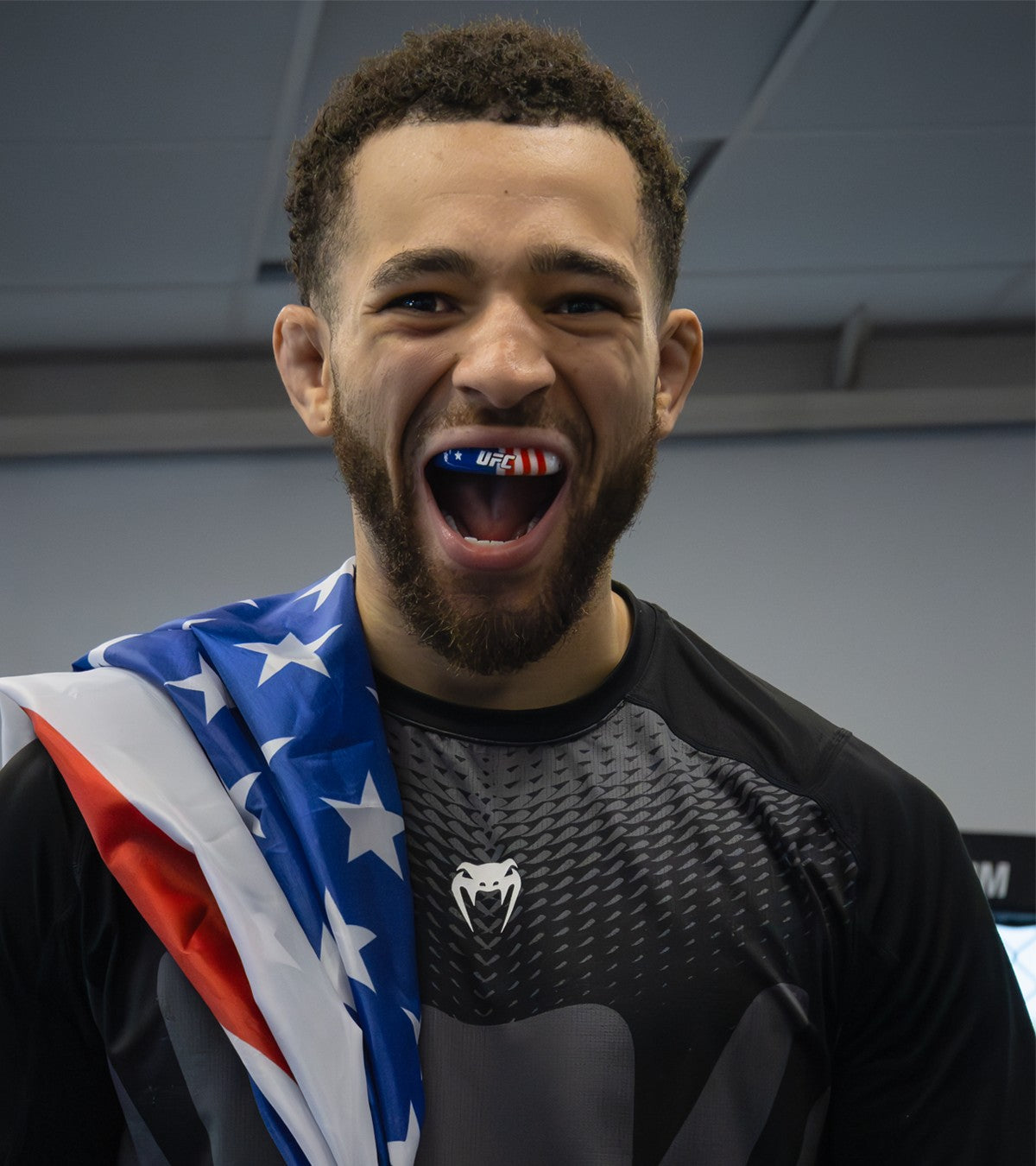 A UFC figher with a US flag draped on his shoulder wearing the OPRO Instant Custom-fit Stars and Stripes mouthguard.