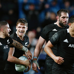 New Zealand rugby players in black jerseys celebrating together on the field during a match.