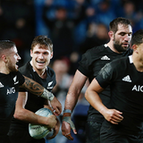 New Zealand rugby players in black jerseys celebrating together on the field during a match.