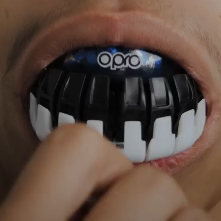 Person wearing a black and white keyboard-themed mouthguard with 'Opro' branding.